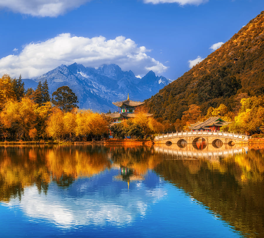 paise de un templo entre las montanas reflejandose en un lago.