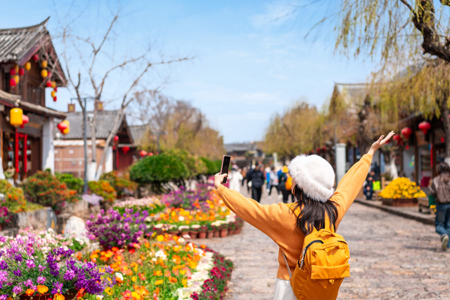 mujer de vestida de aparillo apreciando la ciudad de lijiang.